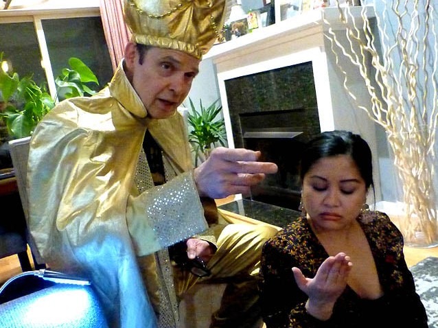 Mister Vibe dressed in a gold suit and turban reads the palm of a woman.