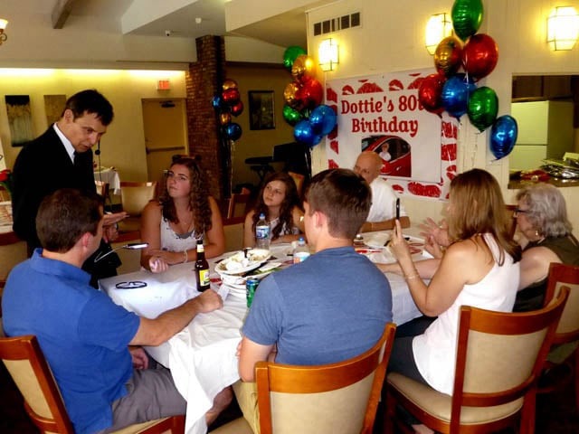 Mister Vibe reads the palms of a group of people seated around a table.