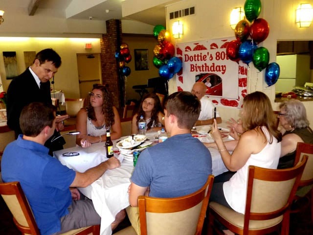 Mister Vibe reads the palms of a group of people seated around a table.