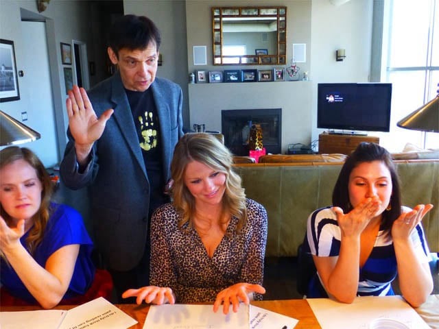 Mister Vibe reads the palms of three women seated at a table.