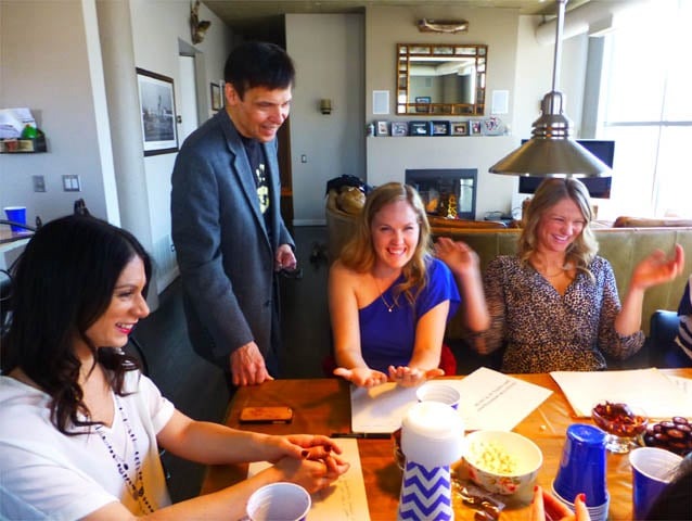Mister Vibe reads the palms of three women seated at a table.