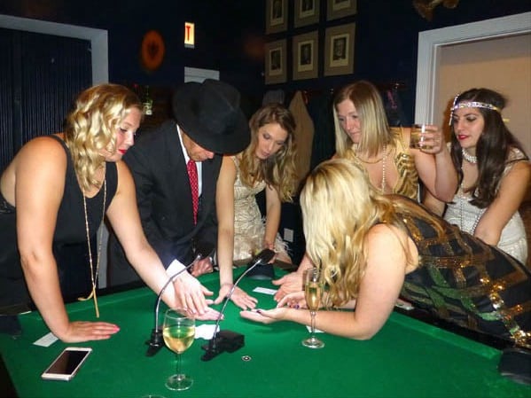 Mister Vibe reads the palms of women gathered around a pool table. 