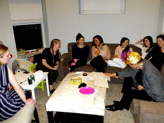 Mister Vibe reads the palms of a group of women seated on a living room sofa.