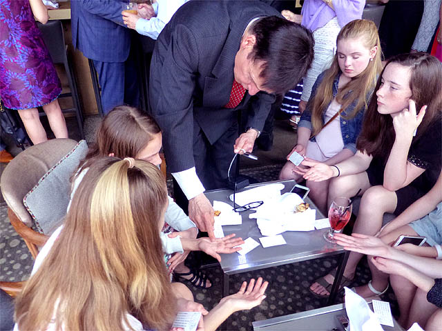Mister Vibe reads the palms of seated teen girls at a Bat Mitzvah party.