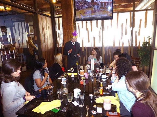 Mister Vibe speaks to a group of women seated at a large restaurant table.