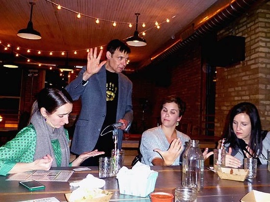 Mister Vibe reads the palms of a group of women seated at a table.