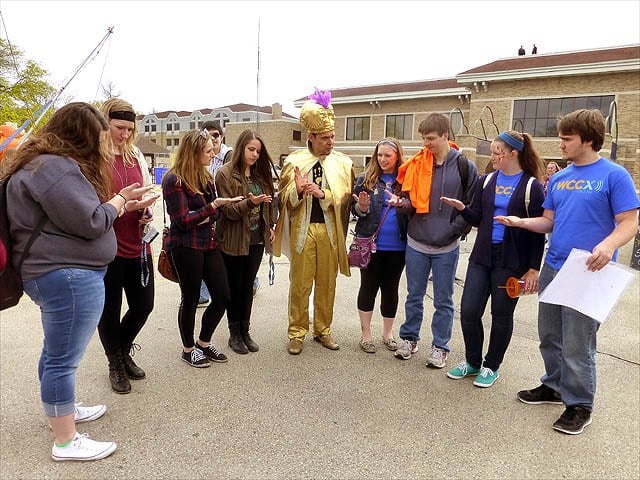 Mister Vibe reads palms of eight standing teens outdoors.