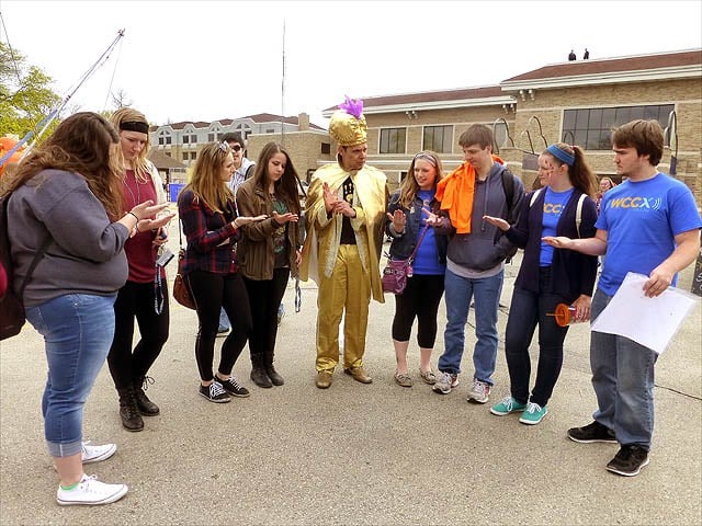 Mister Vibe reads palms of eight standing teens outdoors.