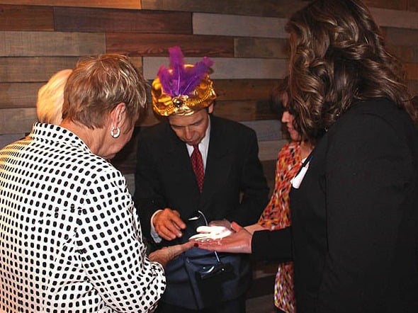 Mister Vibe reads the palms of a group of people at a trade show.