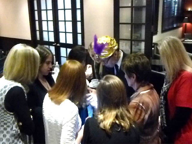 Mister Vibe reads palms surrounded by a group of teen girls.