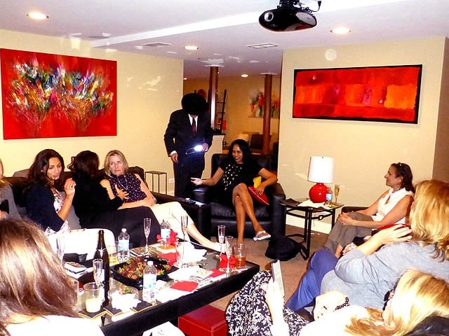 Mister Vibe read palms in a living room full of seated women.