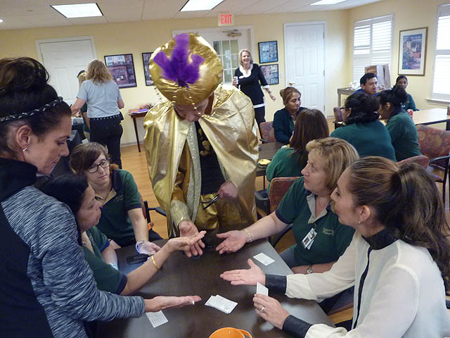 Mister Vibe reads the palms of a group of women gathered around a table.