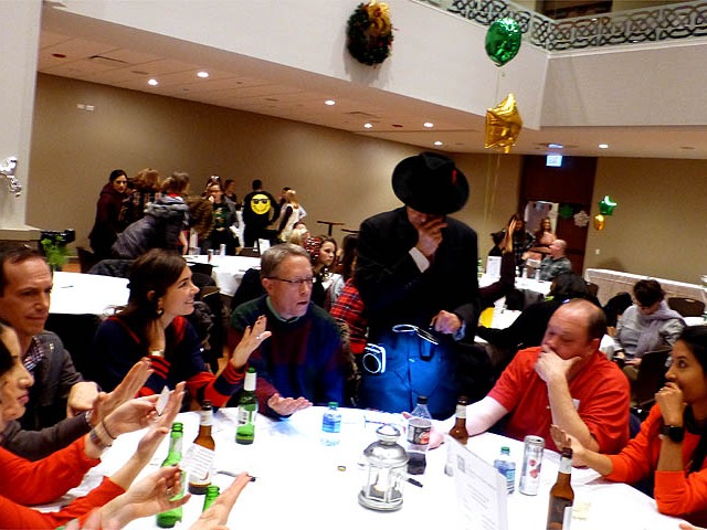A table full of guests at a banquet getting their palms read by Mister Vibe..