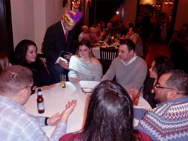 Mister Vibe reads the palms of a group of people seated around a table in a restaurant.