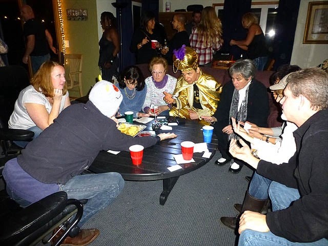Mister Vibe reads palms of a group of people seated in a living room.