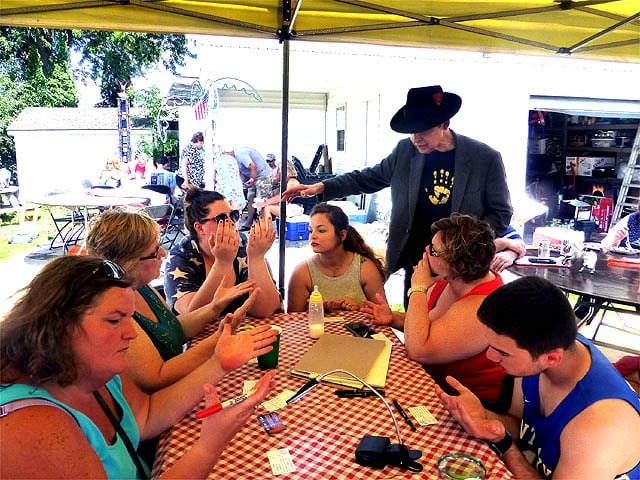 Mister Vibe reads the palms of a group of people sitting at a picnic table outdoors.