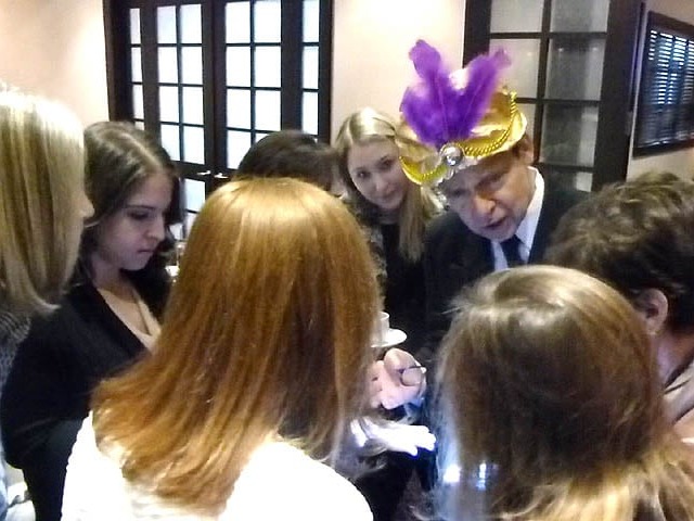 Mister Vibe reads palms surrounded by a group of teen girls.