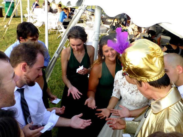 Mister Vibe reads the palms of the bride and her guests at an outdoor wedding reception.
